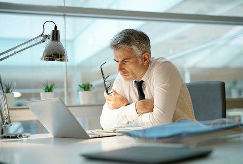 Businessman working on laptop in office, being concerned